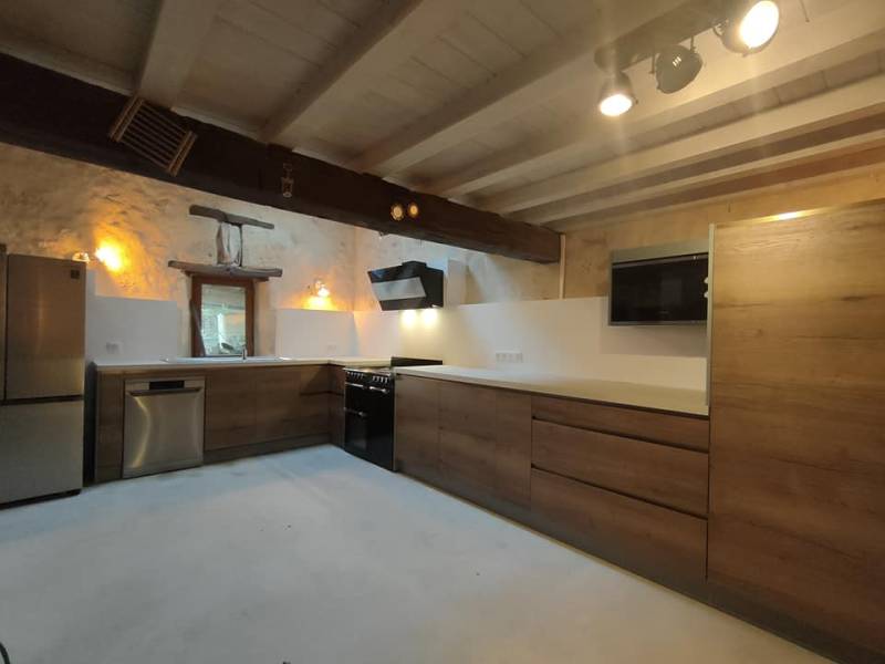 Grande cuisine en bois foncé sans poignée e plan de travail clair à Saint Sulpice Les pommiers proche de Bordeaux