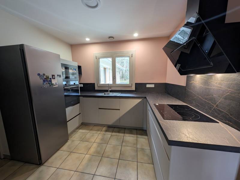 APRÈS : Cuisine sur mesure gris clair (Dove) avec plan de travail céramique Laurent. Design lumineux et moderne.