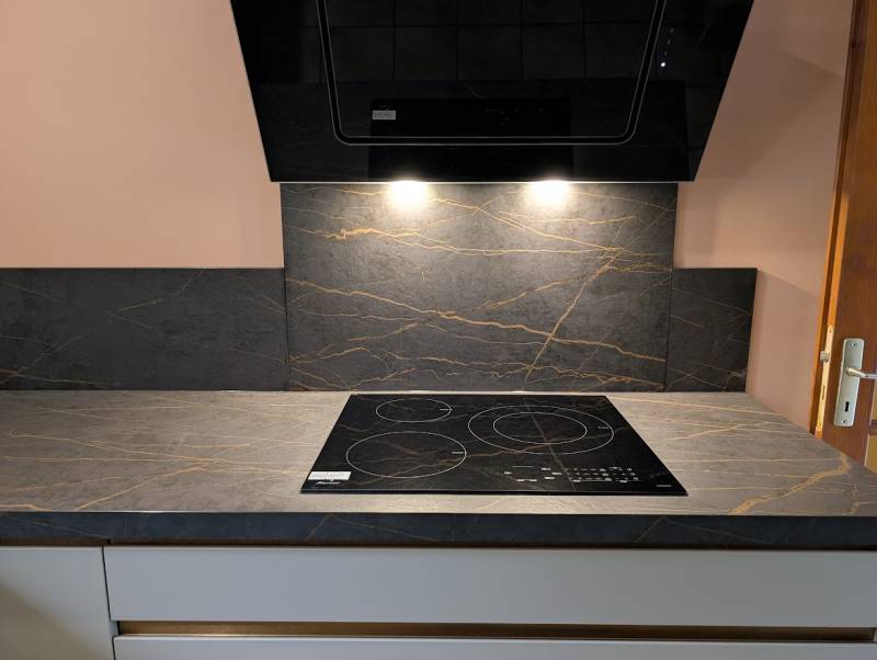 Détail des façades gris clair et de la plaque à induction dans cette cuisine sur mesure près de La Brède.