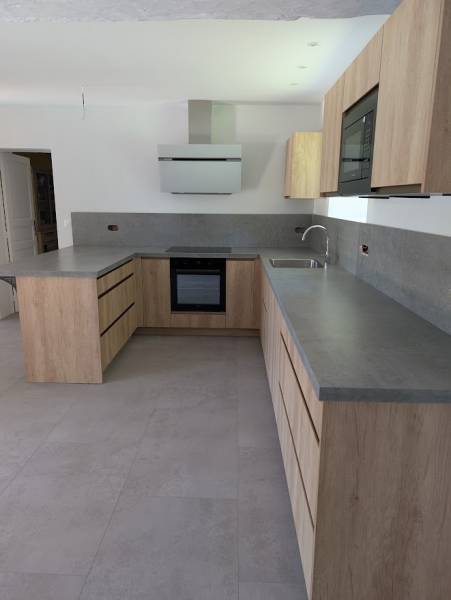 Cuisine bois clair sans poignée avec plan de travail gris clair et four sous cuisson à Rions en Gironde