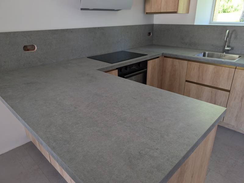 Cuisine en U colori bois clair et plan de travail gris clair à Rions